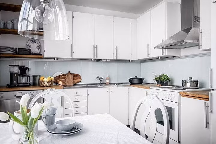 Sử dụng đồ cùng tông màu với tủ bếp trắng, kệ bếp kính phía sau, bàn ăn và kệ bằng gỗ.