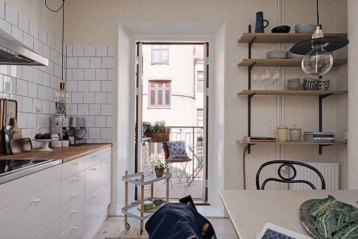 Với những nhà bếp có phong cách giản dị, tường bếp lát gạch hoa vuông màu trắng cùng tông với tủ bếp. Bàn ăn, giá đựng đồ gia dụng sử dụng gỗ. Nhà bếp cũng được bố trí ở khu vực có ban công, tạo sự thông thoáng khi nấu nướng.