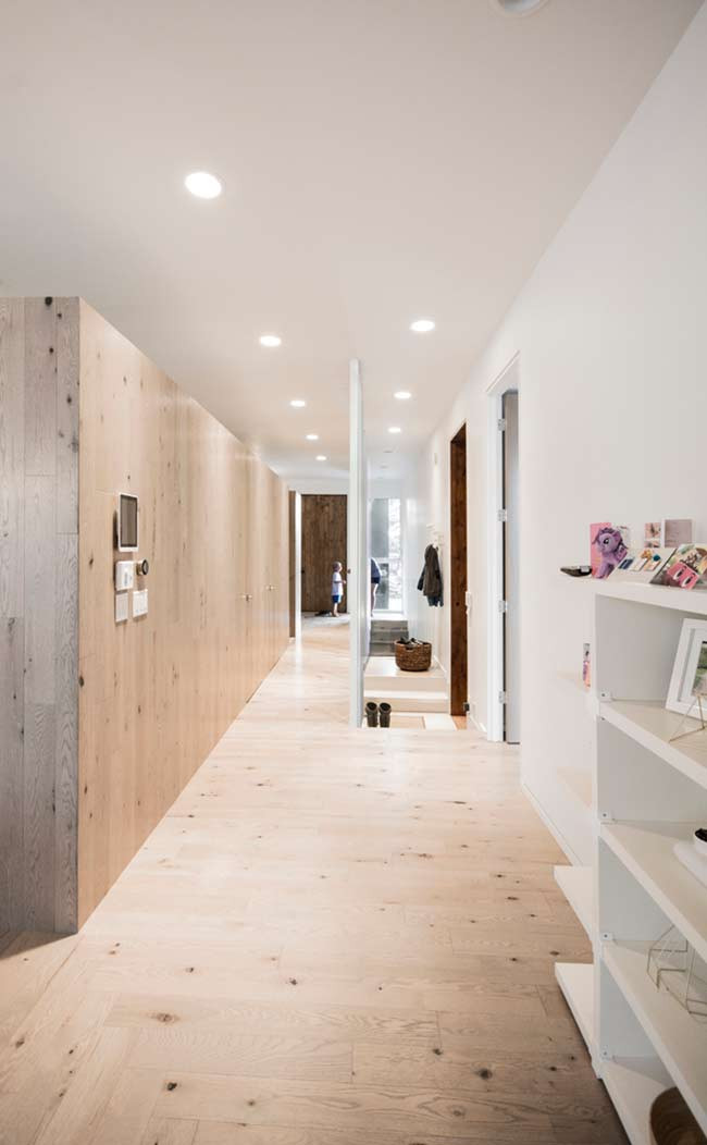 Cánh cửa phòng ngủ được ngăn cách với không gian sống bằng một tấm chắn cây gỗ thích màu trắng giúp kéo dài dạng hình của các cột bên ngoài qua ngôi nhà.