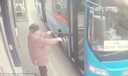 Người đàn ông dùng ô để mở cửa xe buýt sắp chuyển bánh.