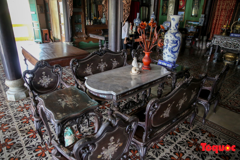 Ngôi nhà nổi bật với ba bộ bàn ghế cổ đẹp và một chiếc sập gụ được trang trí bằng khảm trai tinh xảo cùng những đường nét trạm trổ mềm mại.