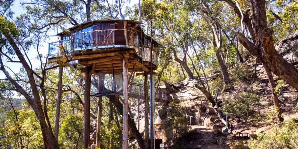 Ngôi nhà trên cây ở dãy núi Blue Mountains, Bilpin, Úc Khi bạn nhìn thấy phần bên trong của ngôi nhà trên cây này được bài trí tuyệt đẹp, và toàn bộ ngôi nhà được bao quanh bởi một khoảnh đất riêng rất lớn, bạn sẽ ước mơ được sống ở đây suốt đời. Cửa sổ kính suốt từ trần đến sàn ở tất cả các hướng giúp ánh sáng tự nhiên tràn vào và cho phép bạn ngắm toàn cảnh xung quanh.