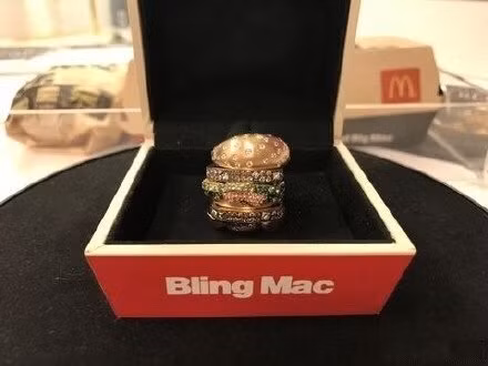 Hộp đựng nhẫn cũng được thiết kế phỏng theo hộp hamburger của McDonald’s, bên trên có ghi dòng chữ Bling Mac và gắn logo của hãng.