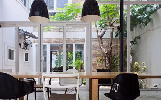 Phòng ăn nhìn ra khoảng sân rồi tới nhà bếp cũng với dãy cửa kéo có thể mở rộng đón nắng và gió.