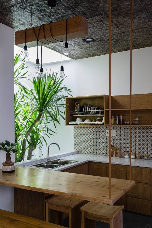 Tủ bếp không cánh cùng lá cọ xanh mang lại cảm giác khoáng đạt. Các vật dụng trong bếp cũng được chủ nhân tinh tế chọn lựa sao cho đồng bộ với cả căn nhà.