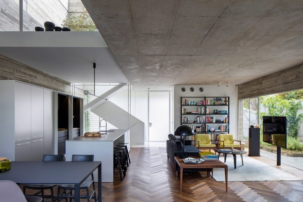 Ngôi nhà có kết cấu chính là bê tông, mặt tiền căn nhà nhìn thẳng ra đường, các bức tường và cửa kính cỡ lớn được sử dụng đem lại cảm giác kết nối giữa bên trong và ngoài nhà. Gỗ được sử dụng làm sàn lót trên nền bê tông. Điều này giúp tăng sự ấm cúng cho căn phòng, đông thời tương phản với màu sắc có phần lạnh lẽo của bê tông.
