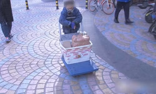 Cậu bé trong mặc một chiếc áo khoác mỏng, phần tay dài kéo xuống phủ kín bàn tay.