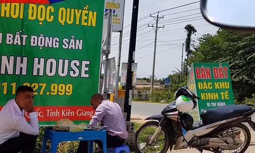 Nhân viên tiếp thị đất dựng pa nô, che dù ngoài vỉa hè để rao bán đất.