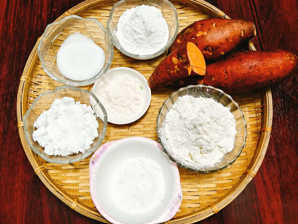 Chuẩn bị nguyên liệu làm món khoai lang kén: 500 gram khoai lang, 40 gram bột nếp, 30 gram bột năng, 30 gram đường, 10 gram bột cốt dừa hoặc nước cốt dừa, 100 gram bột chiên giòn, 10 gram bột sư tử, muối, dầu ăn.