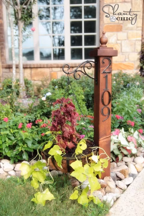 Hãy làm cho cột ghi biển số nhà mình thêm sinh động bằng một chậu hoa với cây dây theo và đừng quên thường xuyên tưới tắm cho chậu hoa này.