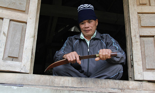 Ông Hiển bên cạnh chiếc dao đi rừng từng gắn bó với ông thời còn hành nghề thầy cúng. Ảnh: PV