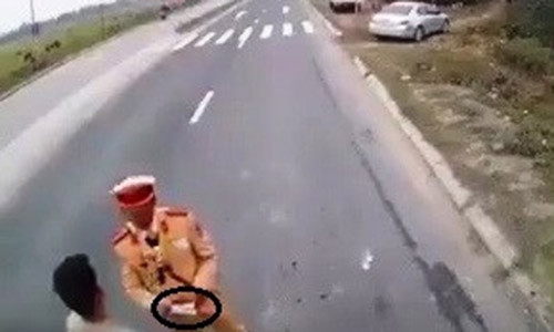 Một cảnh sát giao thông bị cho là nhận tiền mãi lộ trên quốc lộ 21. Ảnh cắt từ clip.