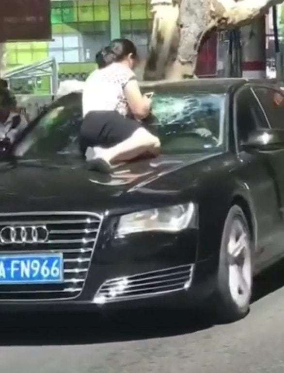 Người vợ nhảy lên mui xe đang chạy của chồng để đánh ghen.