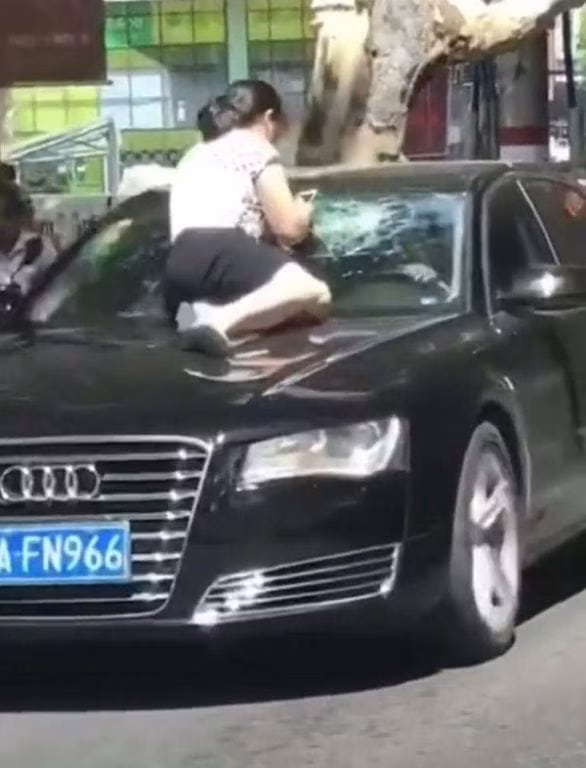 Người vợ nhảy lên mui xe đang chạy của chồng để đánh ghen.