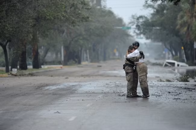 Một thành viên của nhóm tìm kiếm và cứu hộ an ủi một người phụ nữ sau khi cơn bão đột ngột đi qua quê hương của cô.