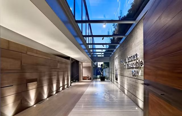 Nhờ sở hữu diện tích hơn 800m², hai nhà thiết kế có thừa không gian để tạo nên một thảm cỏ rộng lớn. Không gian lộ thiên xanh mát này vừa giúp giảm nhiệt mùa hè, vừa là nơi thư giãn, tắm nắng hoặc tổ chức các buổi tiệc ngoài trời. Dãy cửa sổ trần mở ra không gian tràn ngập ánh sáng cho khu sảnh.