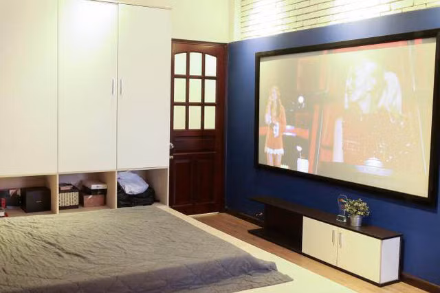 Anh sắm một chiếc tivi 100 inch đặt tại phòng ngủ để giải trí.