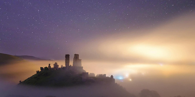 Sương mù vẫn còn giăng kín lâu đài Corfe, Dorset. Từ trên đỉnh đồi, ánh sáng yếu ớt của những tia nắng ban mai đâm xuyên qua màn sương tạo nên một khuôn cảnh huyền ảo, thơ mộng.