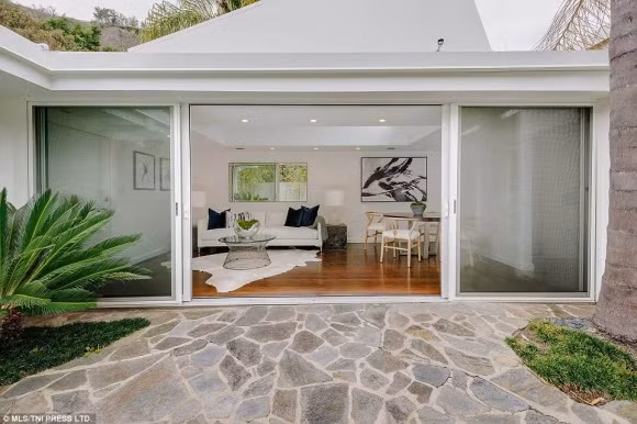 Điểm cộng của căn nhà là có phòng khách rộng lớn với trần nhà cao cùng cửa dẫn ra khu vườn tươi mát bên ngoài. Ngoài ra cơ ngơi trên còn có hồ bơi xanh trọng được bao quanh bởi cây cối và núi non. Trong nhà còn có cả một hầm rượu vang với sức chứa lên đến cả nghìn chai.