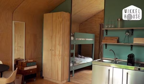 Bước tiếp vào là khu vực bếp nhỏ xinh nhưng chẳng thiếu thứ gì với gam màu xanh lạ mắt, vật dụng làm bếp được đặt gọn gàng trên kệ treo tường. Không gian tuy nhỏ nhưng vẫn đủ chỗ đặt một bộ bàn ăn gỗ xinh xắn để cả nhà cùng nhau thưởng thức bữa ăn.