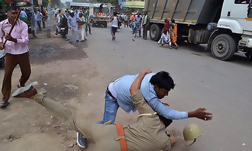 Một người đàn ông xô xát với cảnh sát bên ngoài bệnh viện trong vụ biểu tình phản đối vụ cưỡng hiếp này.