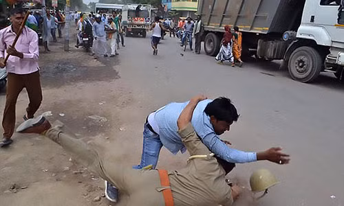 Một người đàn ông xô xát với cảnh sát bên ngoài bệnh viện trong vụ biểu tình phản đối vụ cưỡng hiếp này.