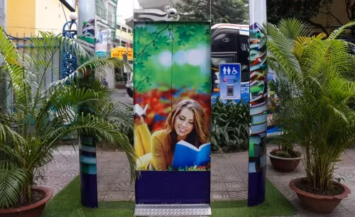 Còn đây là nhà vệ sinh công cộng được thiết kế khá gần gũi thiên nhiên, và miễn phí đặt trên vỉa hè đường Nguyễn Du (quận 1, TP. HCM). Diện tích cabin vệ sinh công cộng này khoảng 2,2m vuông, có kiểu dáng khối vuông bốn góc bo tròn. Nóc cabin vệ sinh được gắn hệ thống pin năng lượng mặt trời.