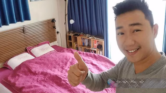 Phòng ngủ rực rỡ của đôi vợ chồng trẻ với bộ ga gối màu hồng kết hợp với rèm cửa màu xanh.