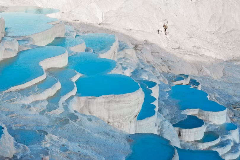 7. Pamukkale Pamukkale được biết đến với những bậc thang màu trắng xanh rực rỡ do nước từ suối nước nóng chảy thành thác nước bị hóa đá. Cảnh quan siêu thực này đã được tạo ra khi những dòng nước giàu canxi chảy qua mép của vách đá và sau đó khi chúng nguội đi, cứng lại tạo thành những bậc thang lộng lẫy.