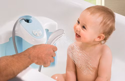 Để giúp trẻ không sợ nước, bước khởi đầu tốt nhất là để bé thích thú mỗi khi được tắm ở nhà. Có thể cho bé chơi trò "tắm mưa" dưới vòi hoa sen khi tắm. Nước vòi sen nhẹ nên các bé thường không sợ khi nước chảy từ đầu xuống và có vẻ thích thú trong thời gian tắm. Ảnh: kidsplaza