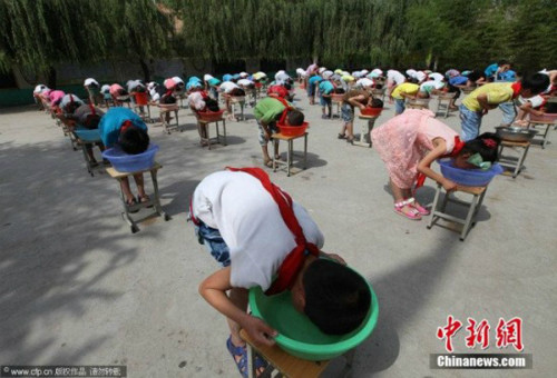 Một cách khác cũng giúp bé làm quen với nước là hướng dẫn các bé vốc nước lên mặt tự rửa rồi thấm lại bằng khăn, thay vì mẹ dùng khăn rửa cho bé. Ngoài ra, cha mẹ cùng con thi xem ai "lặn' lâu hơn bằng cách úp mặt vào một bát nước cũng là phương pháp giúp bé tiếp cận với nước nhanh hơn. Ảnh: chinanew