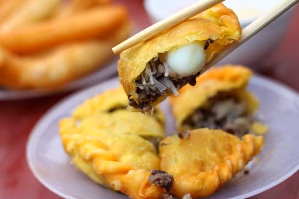 Bánh rán ngọt. Những chiếc bánh rán lúc lắc vàng rộm phủ kín bởi lớp vừng trắng thơm phức bên ngoài và phần nhân đỗ bùi ngọt bên trong sẽ một món ăn tuyệt vời và vô cùng rẻ. Mỗi cái bánh rán chỉ 2.000-3.000 đồng, chỉ cần 3 cái là đã đủ cho một bữa sáng. (Ảnh: Ngoisao).