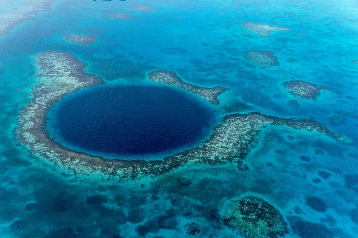 Hố xanh khổng lồ (Great Blue Hole). Vực sâu này có hình tròn, đường kính chừng 300 mét và sâu hơn 100 mét. Vực sâu này vốn hình thành từ một hệ thống hang động đá vôi trong suốt kỷ băng hà. Khi nước biển dâng cao, trần động sụp xuống tạo thành vực sâu như hiện nay. Ảnh The Unknown Blue