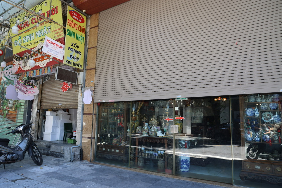 Một số cửa hàng vẫn tranh thủ mở hé cửa để bán hàng cho khách.