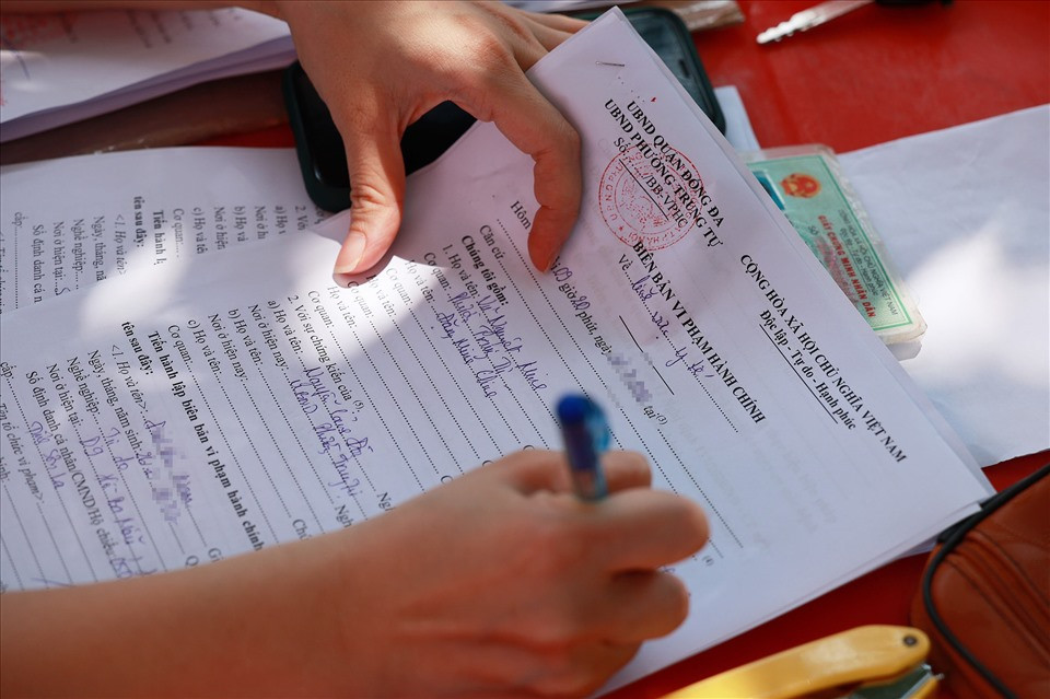 Chốt kiểm soát trên phố Phạm Ngọc Ngọc Thành lập biên bản xử lý các trường hợp ra đường không có lý do. Ảnh: Hải Nguyễn