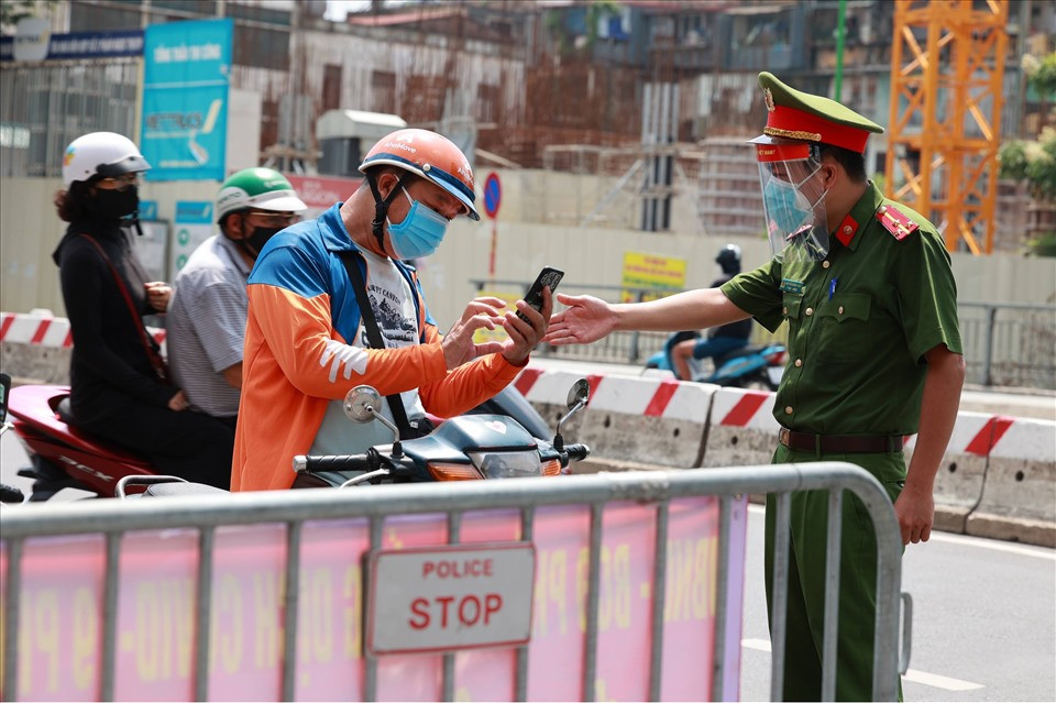 Tại các chốt kiểm soát phòng dịch, lực lượng chức năng phải liên tục phát loa nhắc người đi đường cầm sẵn giấy tờ đi đường trên tay. Hàng loạt phương tiện bị dừng để công an, dân phòng… kiểm tra. Nhiệt độ ngoài trời là 38°C nhưng lực lượng chức năng vẫn đội nắng kiểm soát, phòng dịch COVID-19. Ảnh: Hải Nguyễn
