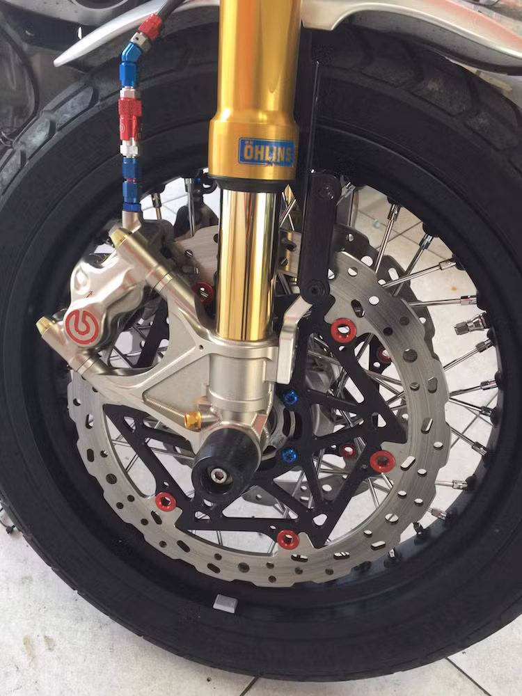 "Dàn chân" trước của chiếc Scrambler đã được nâng cấp với bánh căm kèm cặp phuộc Ohlins USD, trong khi hệ thống phanh chuyển từ đĩa đơn sang đĩa đôi với heo Brembo Caliper .484 dành riêng cho xe độ.