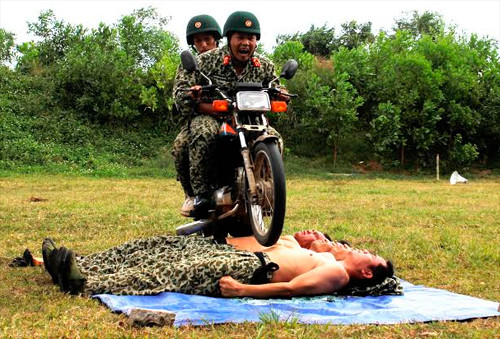 Chiến sĩ Đặc công Việt Nam nằm trên đất để xe máy trườn qua.