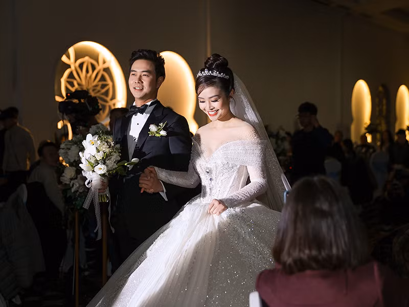 Cô dâu chú rể nắm tay không rời khi bước vào lễ đường.