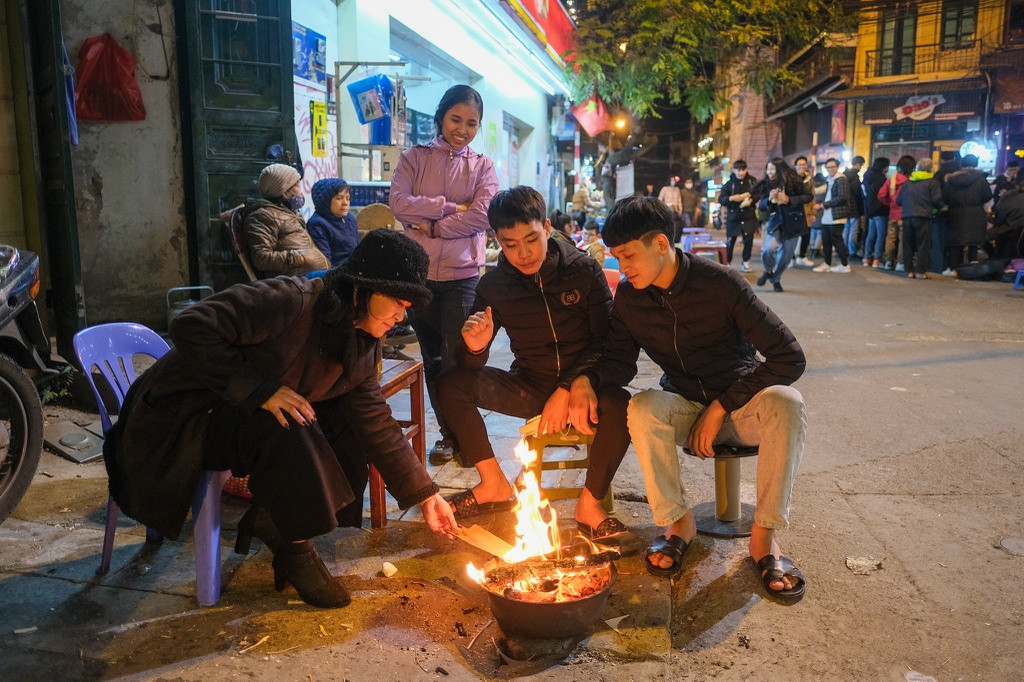 Cảnh đốt lửa sưởi ấm xuất hiện từ chập tối. "Tuần trước, quán trà chanh của tôi kín khách nhưng hôm nay vắng quá. Trời rét nên mọi người ra ngoài cũng ít hơn hẳn", chị Hường (chủ quán nước trên phố Đào Duy Từ) nói.
