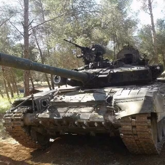 Đây là chiếc T-90 thứ hai bị bắt sống ở Syria, chiếc thứ nhất bị tóm vào ngày 18/4 hiện vẫn chưa rõ tung tích. Chiếc T-90 trong ảnh bị mất toàn bộ giáp ERA bọc quanh bên phải tháp pháo cùng đèn nhiễu Shtora-1.