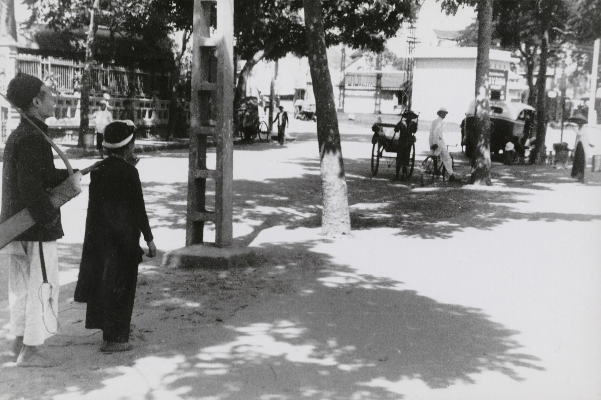 Cô gái trẻ dắt người cha mù đi hát dạo gần quảng trường Négrier, nay là quảng trường Đông Kinh Nghĩa Thục (ngã năm bờ hồ). Ảnh: Musée de l'Homme.