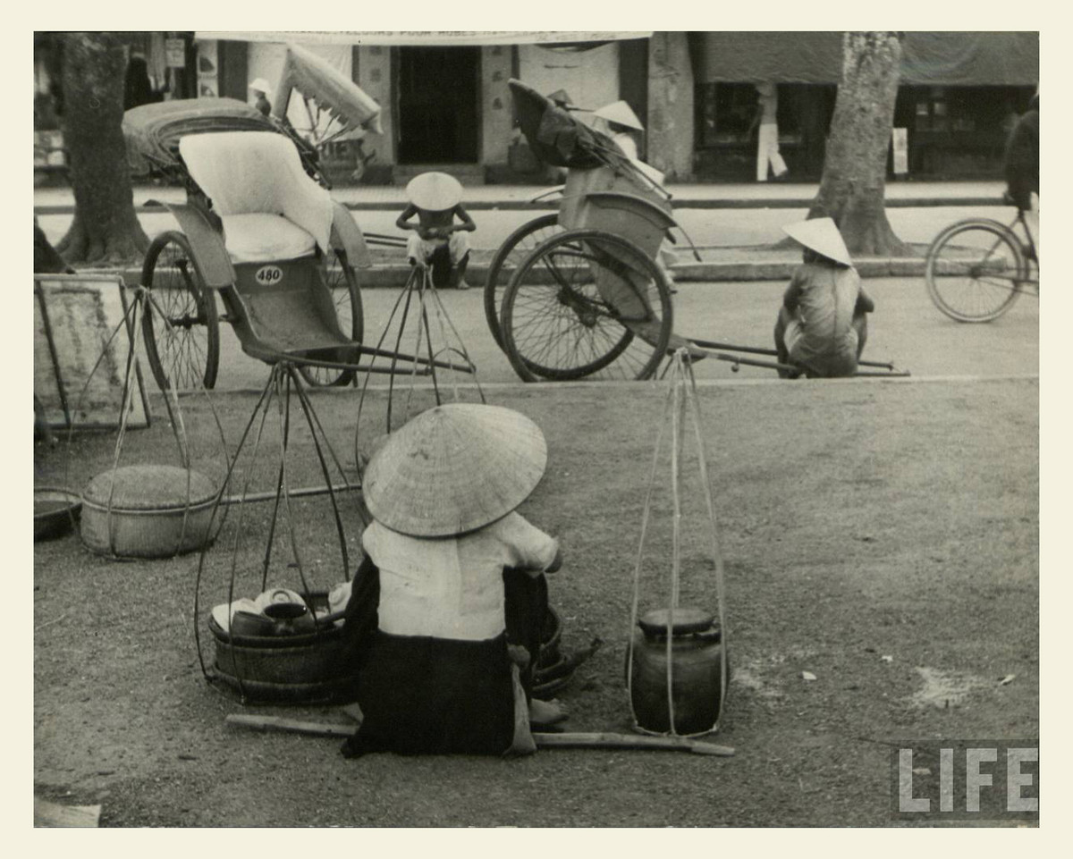 Người bán hàng rong và phu kéo xe trên đường phố Huế. Ảnh: Life.