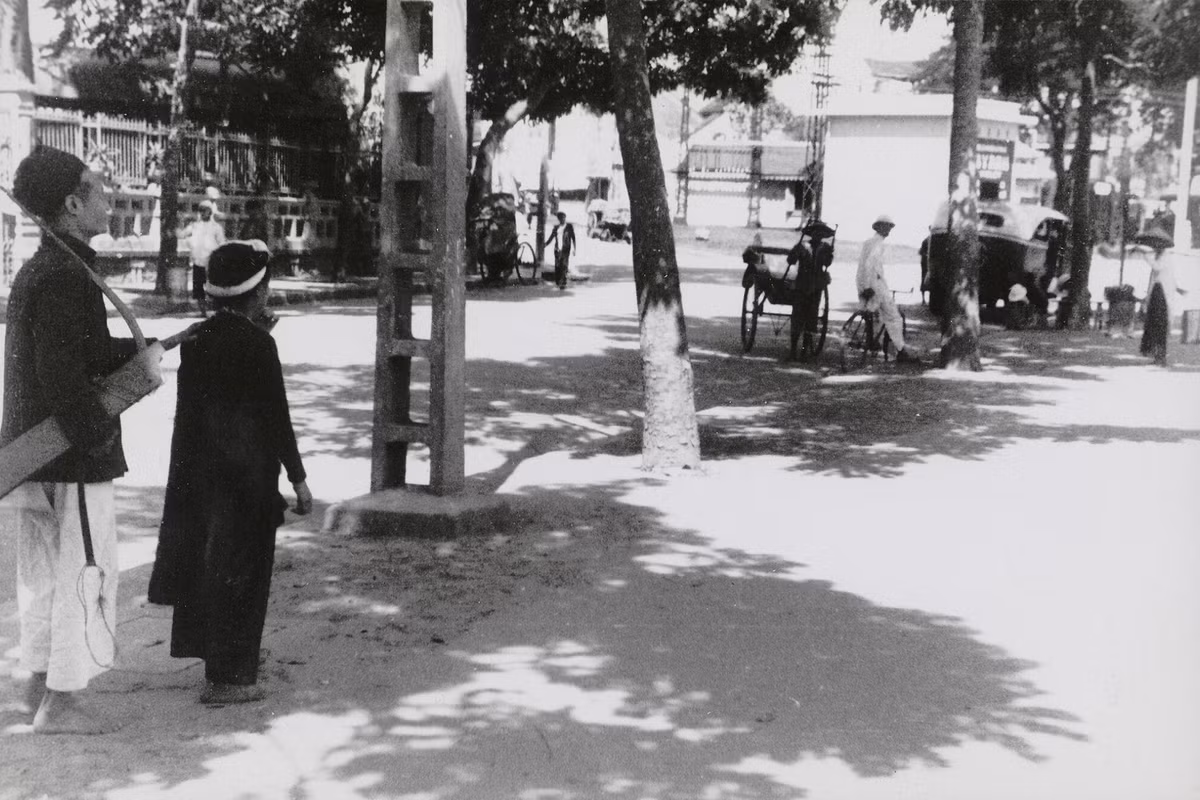 Cô gái trẻ dắt người cha mù đi hát dạo gần quảng trường Négrier, nay là quảng trường Đông Kinh Nghĩa Thục (ngã năm bờ hồ). Ảnh: Musée de l'Homme.