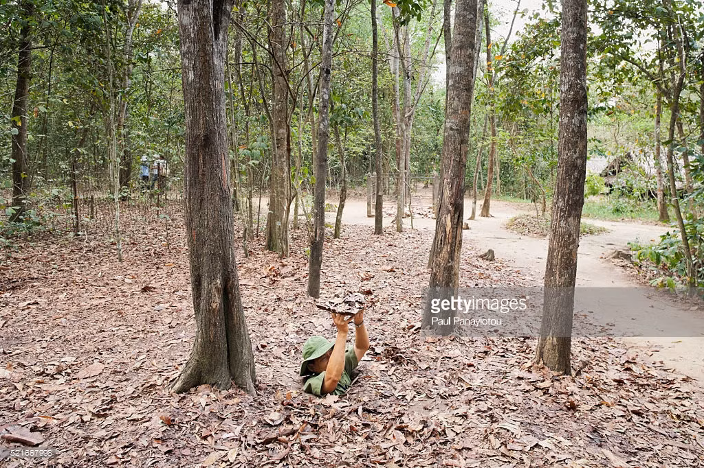 Người hướng dẫn viên trình diễn việc chui xuống một ngách hầm bí mật ở địa đạo Củ Chi. Ảnh: Getty.