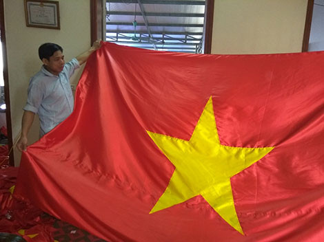 Nghệ nhân Nguyễn Văn Phục với lá cờ mới hoàn thành.