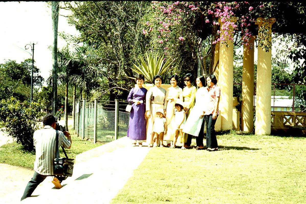 Một nhóm phụ nữ và trẻ em chụp ảnh kỷ niệm dưới giàn hoa giấy trong Thảo Cầm Viên.
