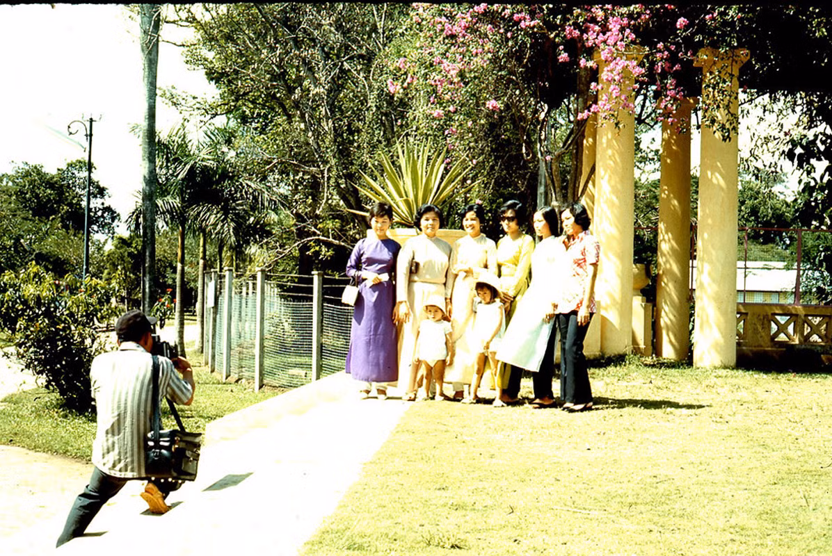 Một nhóm phụ nữ và trẻ em chụp ảnh kỷ niệm dưới giàn hoa giấy trong Thảo Cầm Viên.
