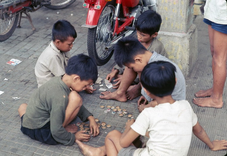 Những đứa trẻ đánh bài ăn “tiền” trên vỉa hè. Tiền ở đây là những chiếc nắp chai.