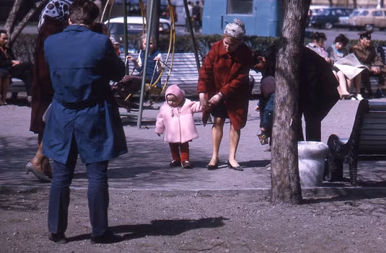 Bé gái lẫm chẫm bước đi khi được mẹ dìu trên phố. Ảnh VT